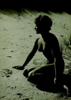 Nahá dívka klečící na pláži